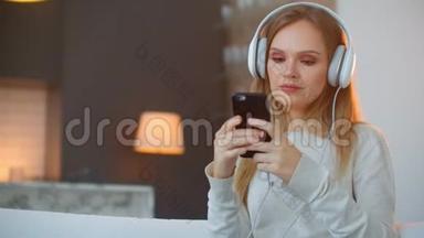 年轻快乐的女人在沙发上听音乐。 年轻快乐迷人的女人在沙发上听音乐。